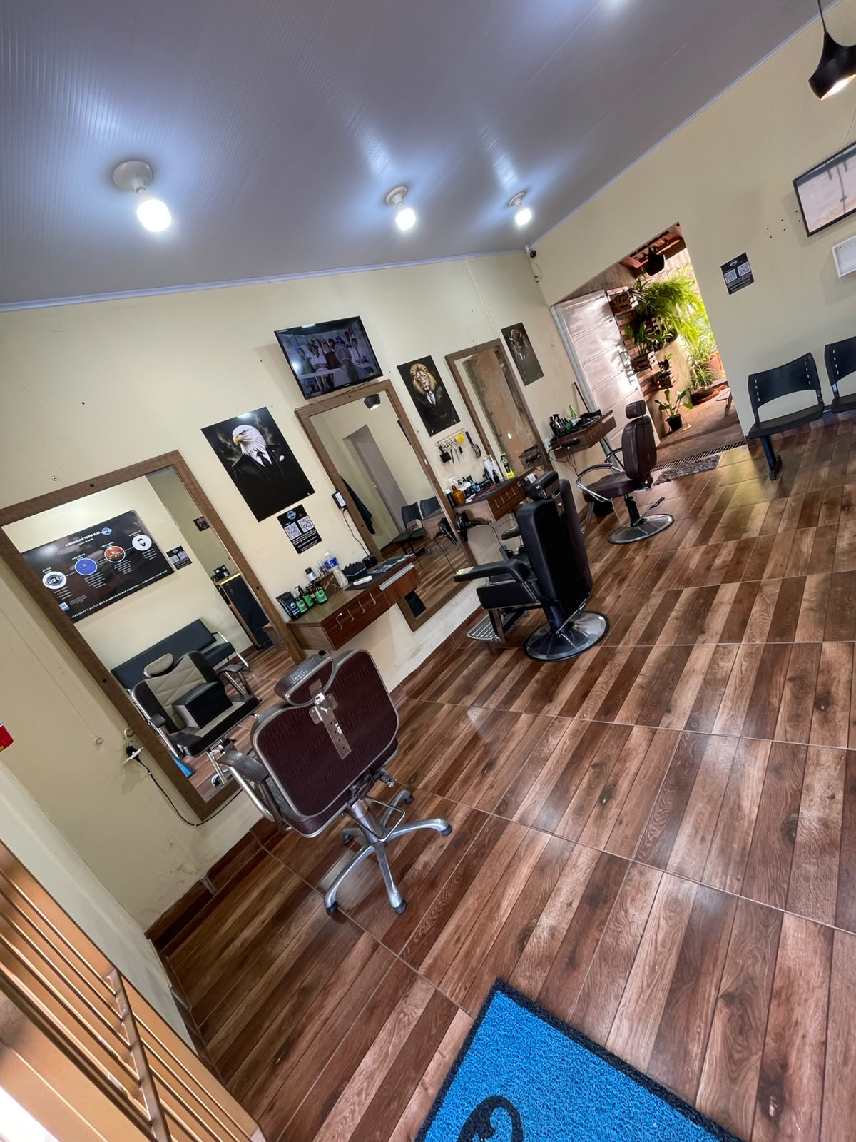 Salão da OLD WEST Barbearia com cadeiras, espelhos e TV